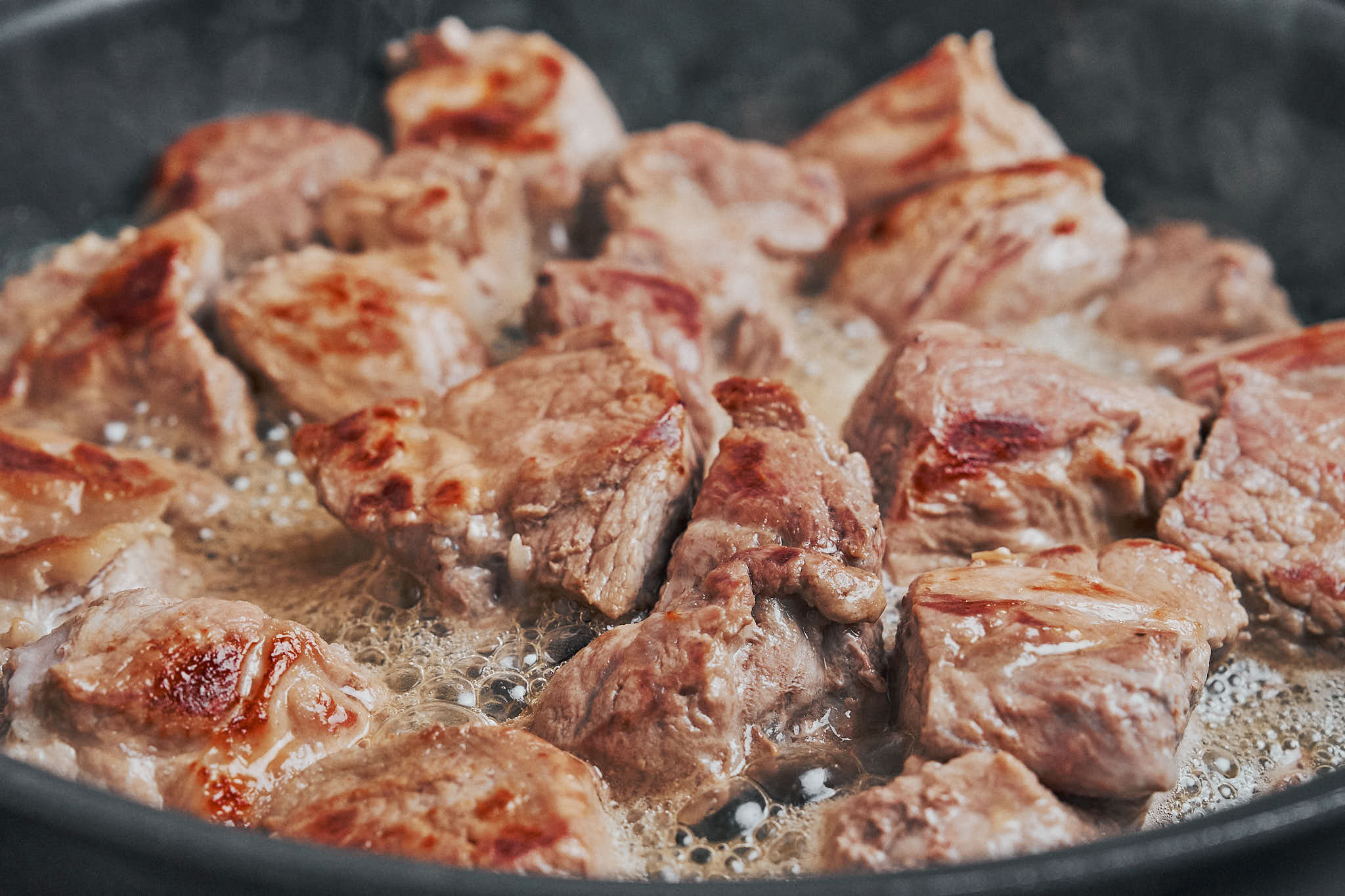 seared pork cubes developing golden crust in skillet