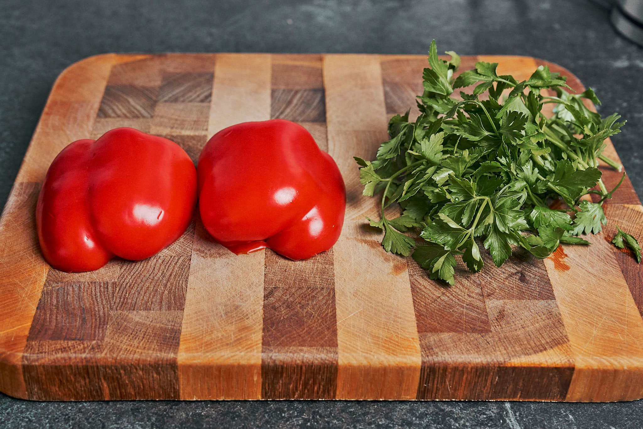 fresh red bell peppers and parsley on wooden cutting board