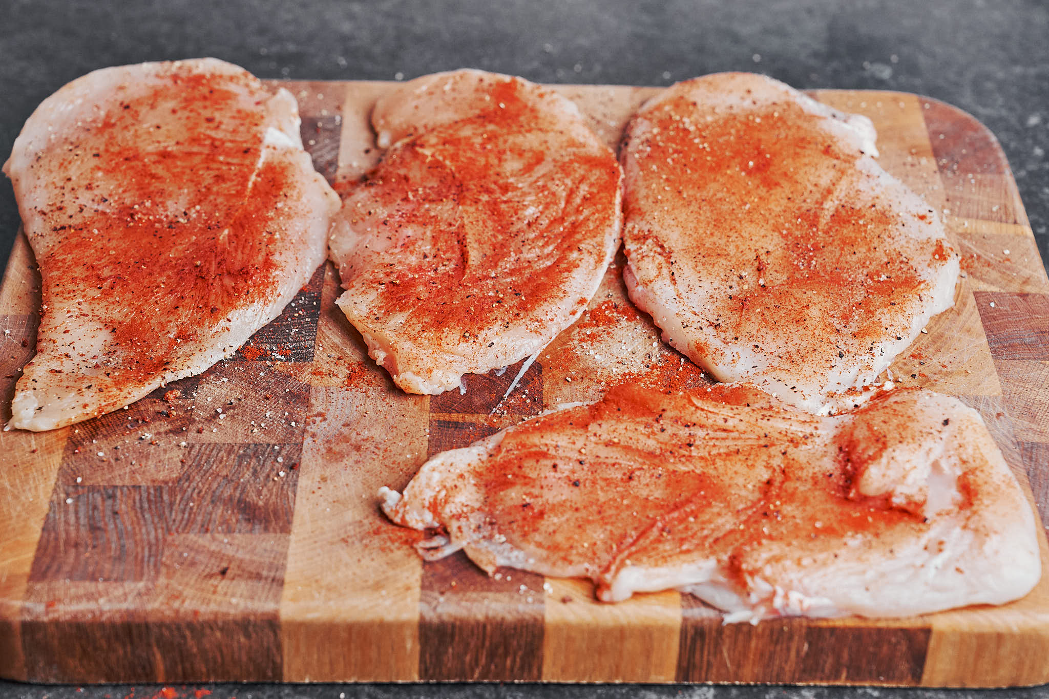 seasoned chicken cutlets with paprika salt and pepper ready to be cooked in a skillet
