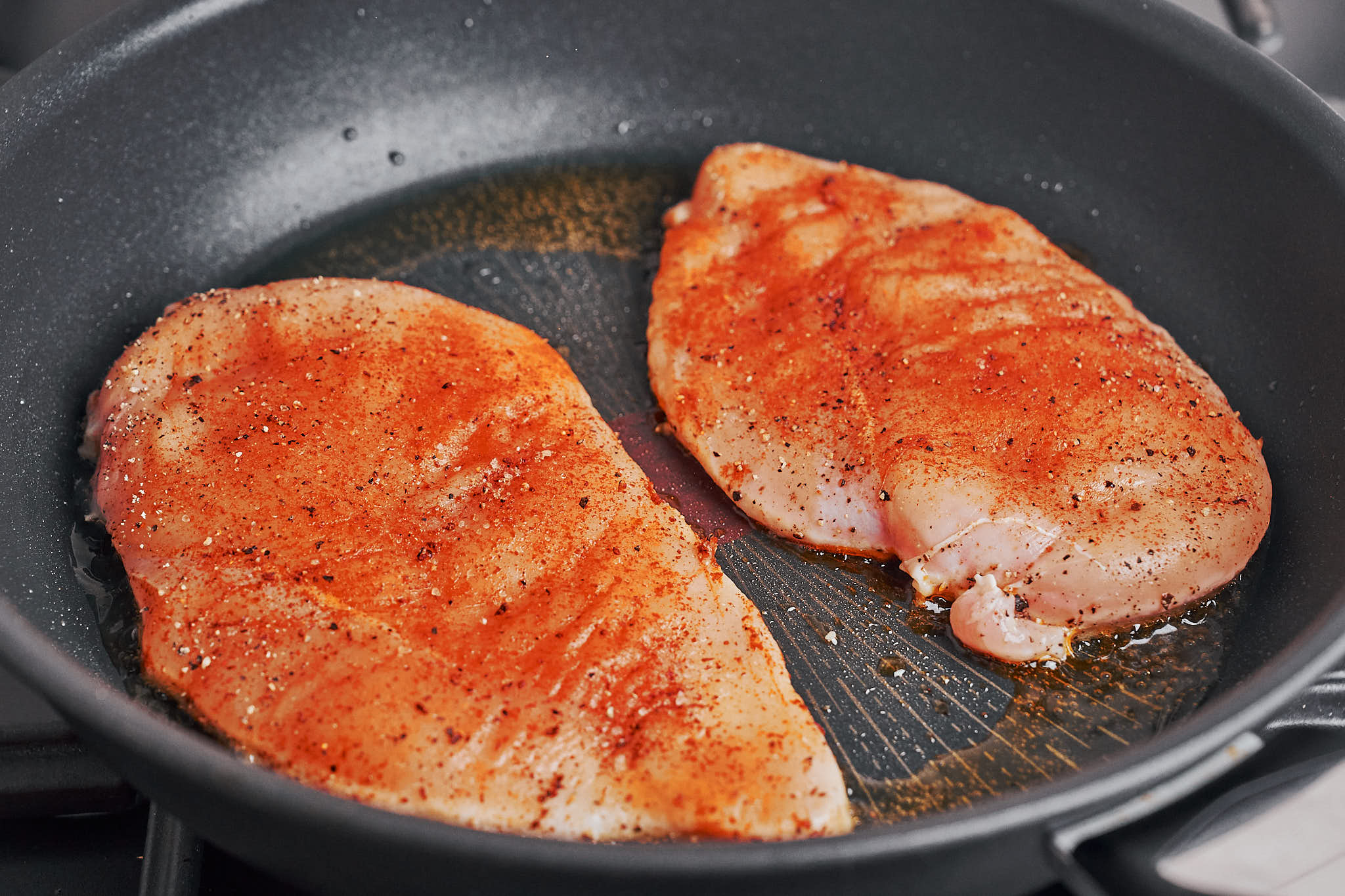 seasoned chicken cooking in a hot skillet to develop a golden crust