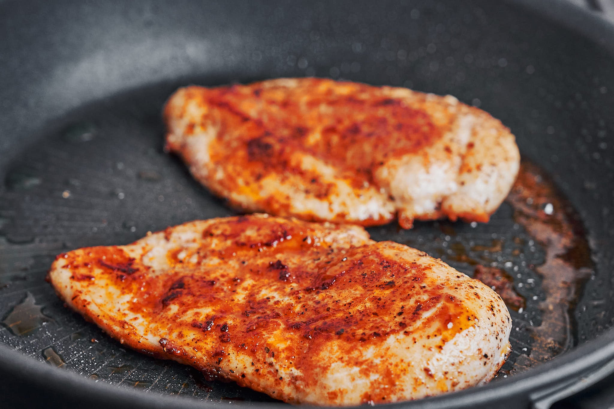 chicken cutlets getting a golden crust while cooking in a skillet