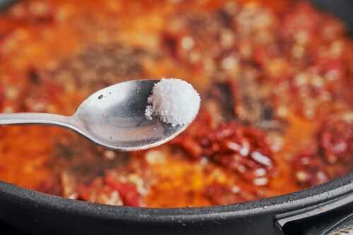 seasoning the sauce with salt to bring the flavors together