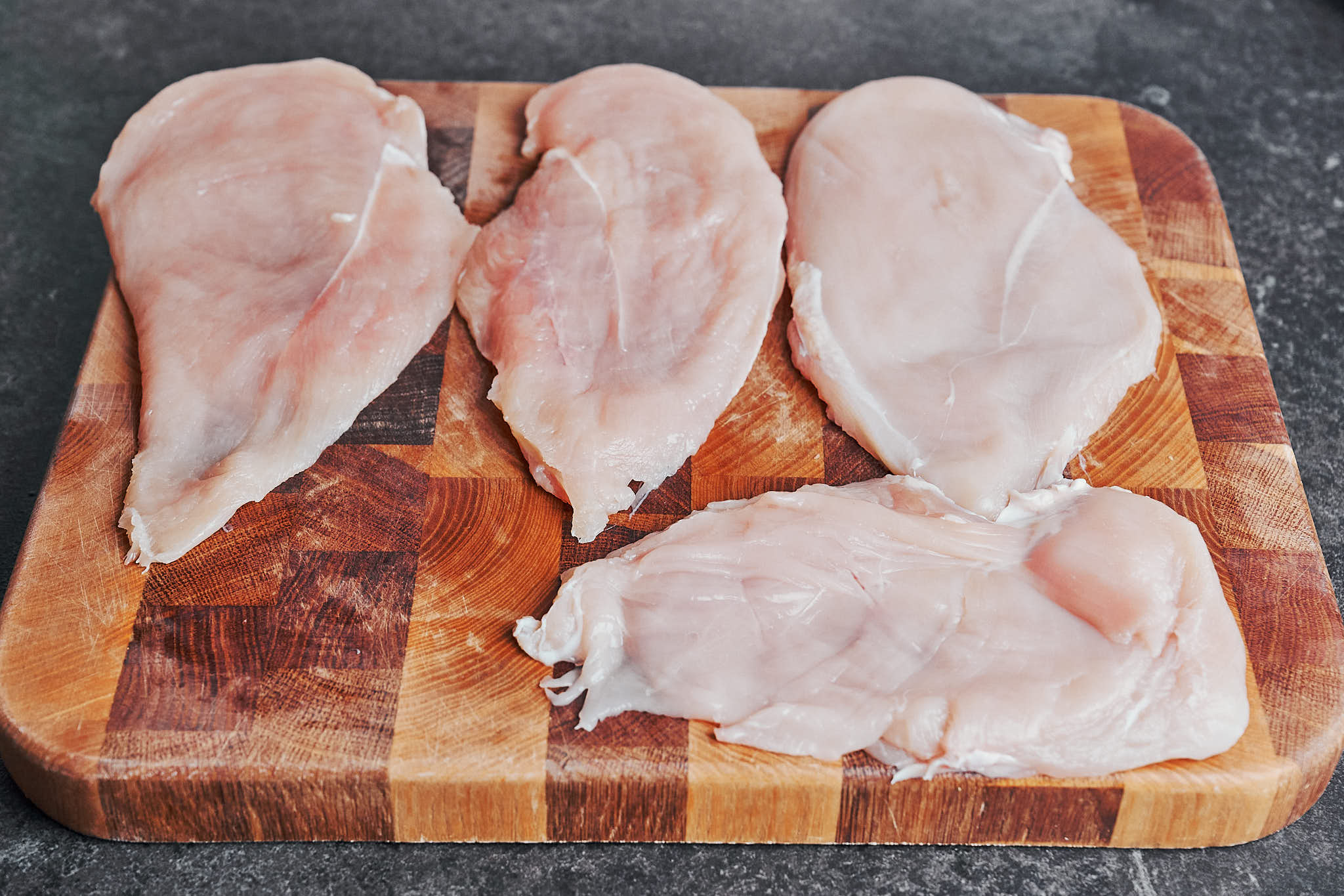 chicken breasts sliced into thinner cutlets on a cutting board for even cooking