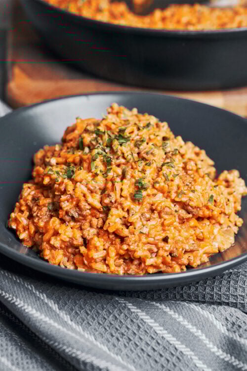 a warm serving of creamy tomato ground beef and rice skillet with fresh parsley on top