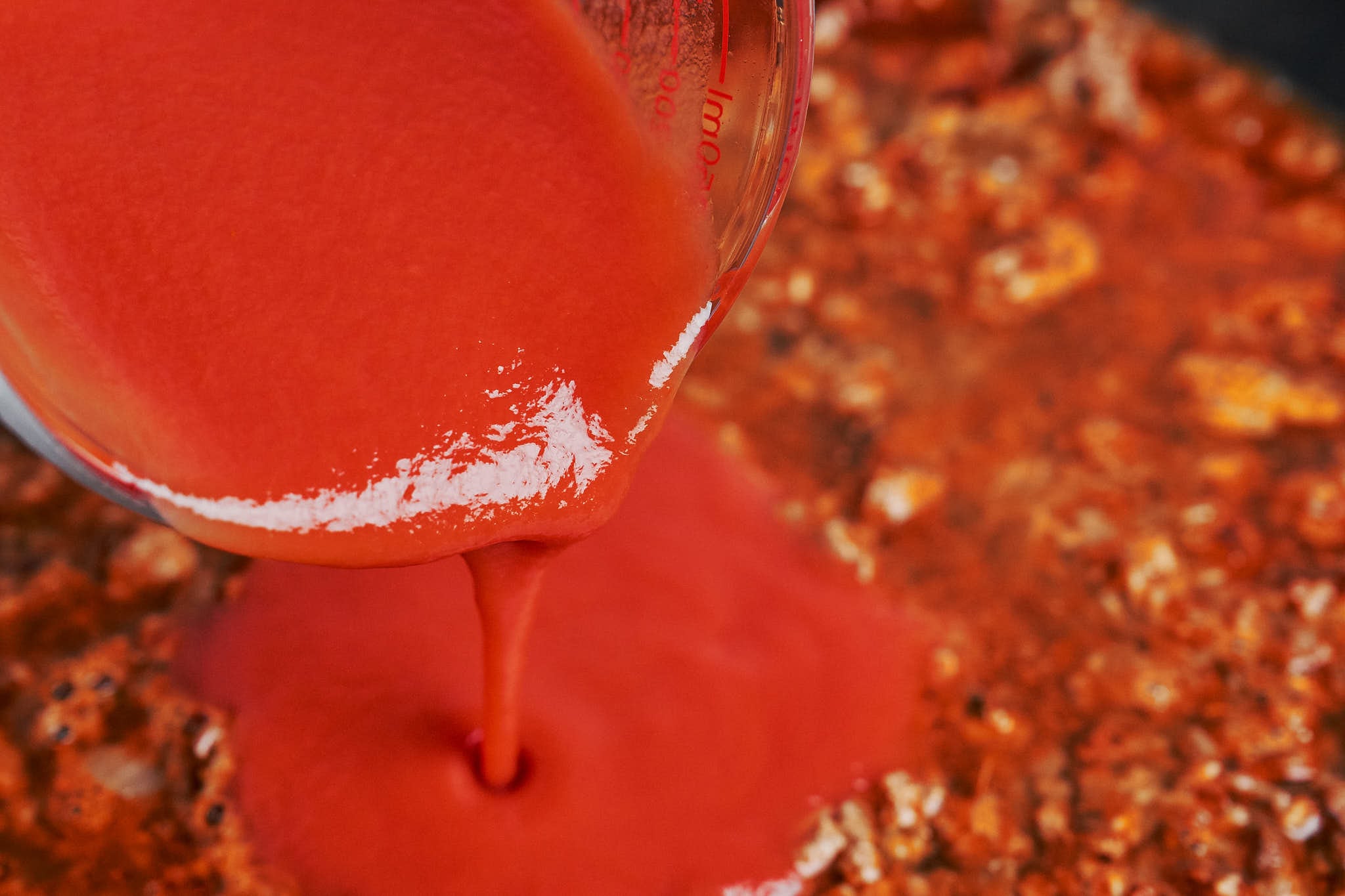 tomato sauce being poured into the skillet to bring everything together into a rich, cozy sauce