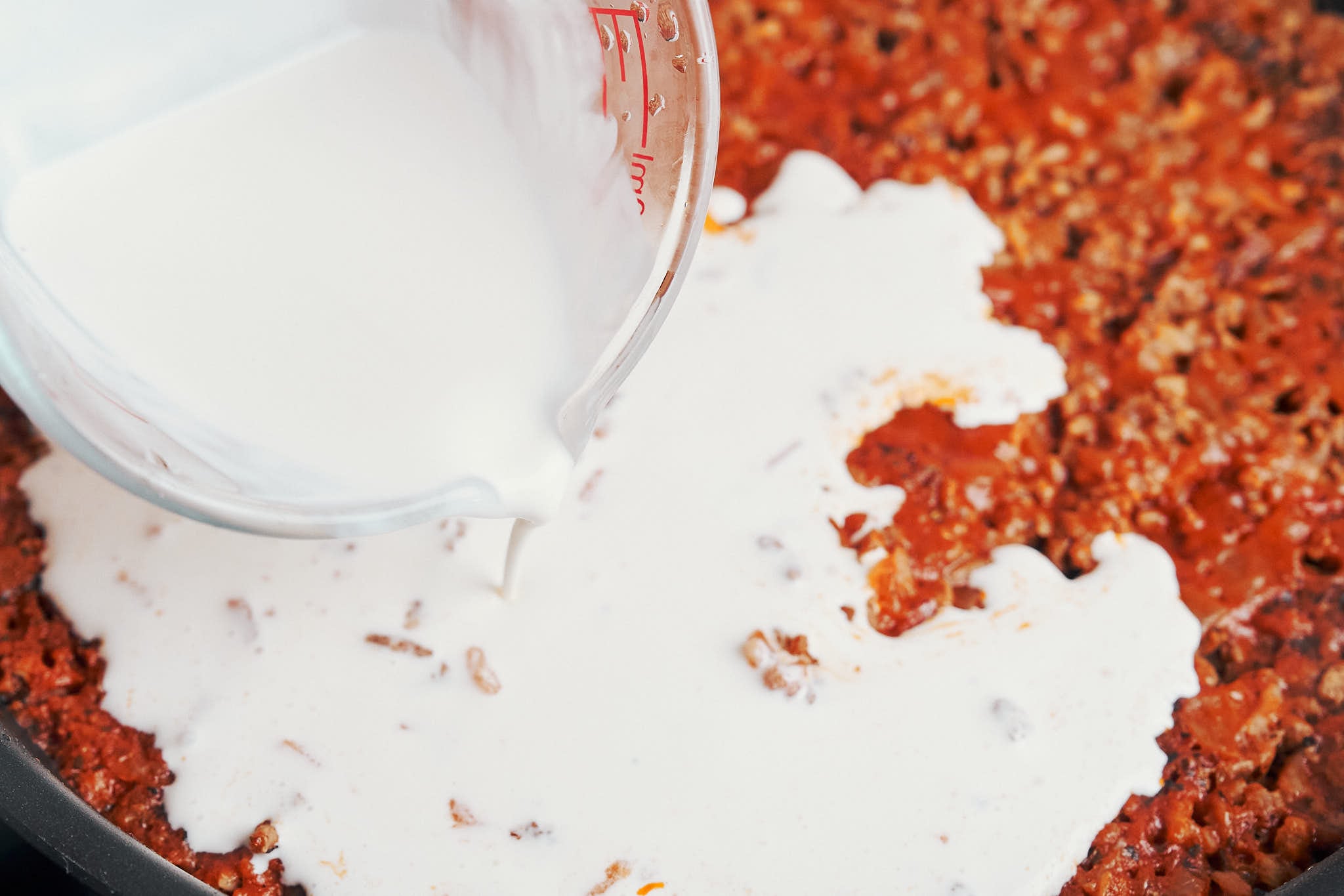 heavy cream being poured in to give the skillet its creamy, cozy finish