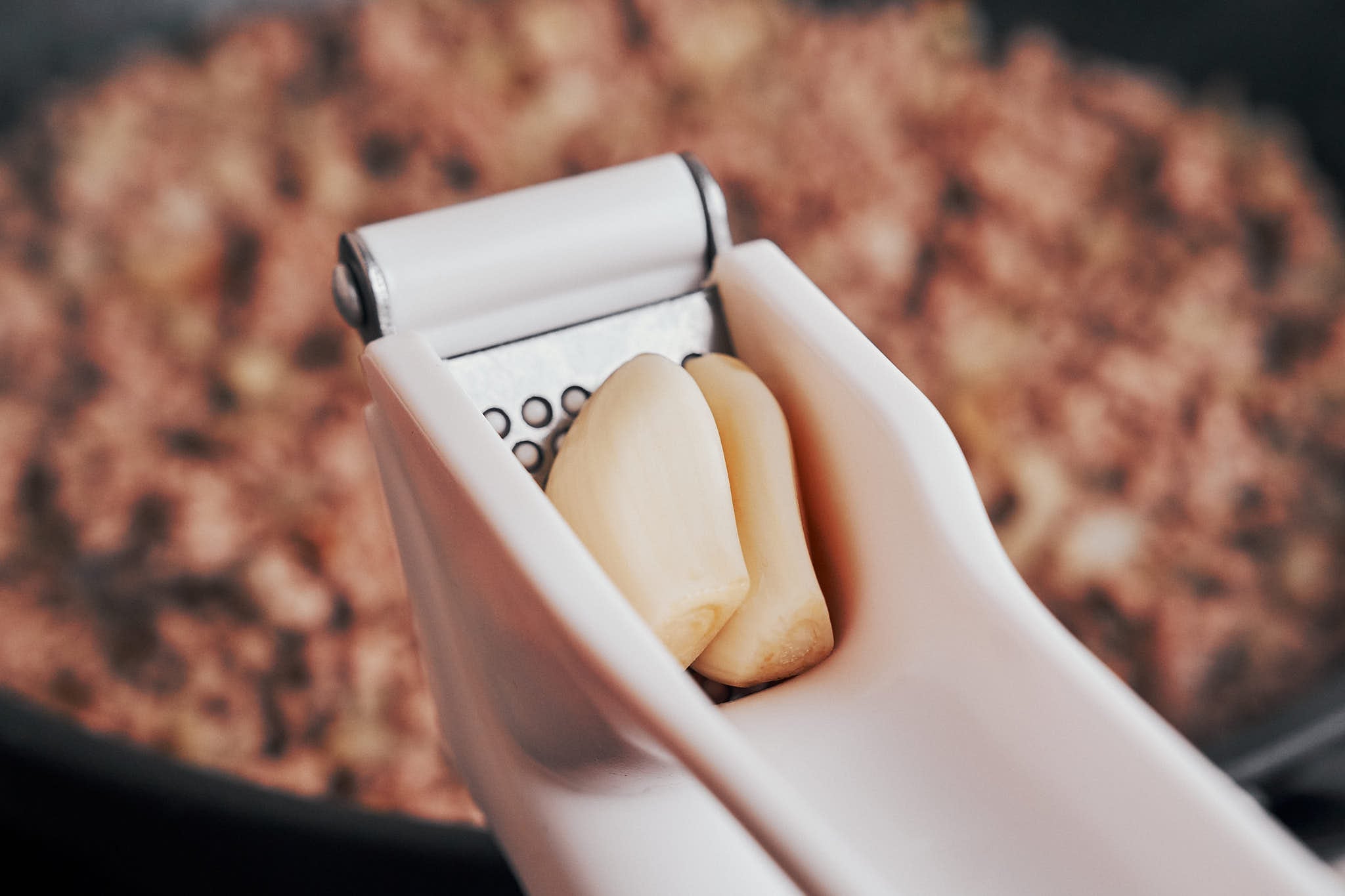 fresh garlic being pressed into the skillet for an extra layer of cozy flavor