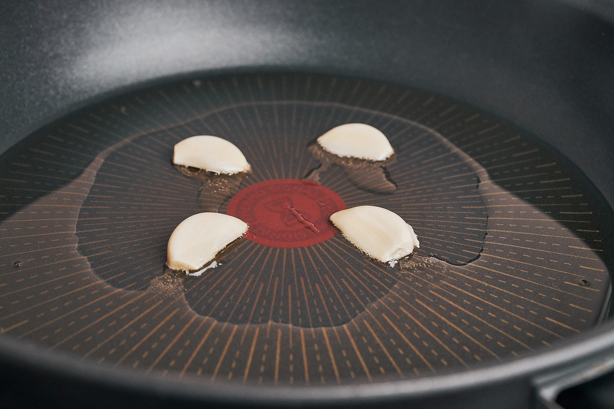 halved garlic gently sizzling in olive oil for a flavorful chicken and rice skillet
