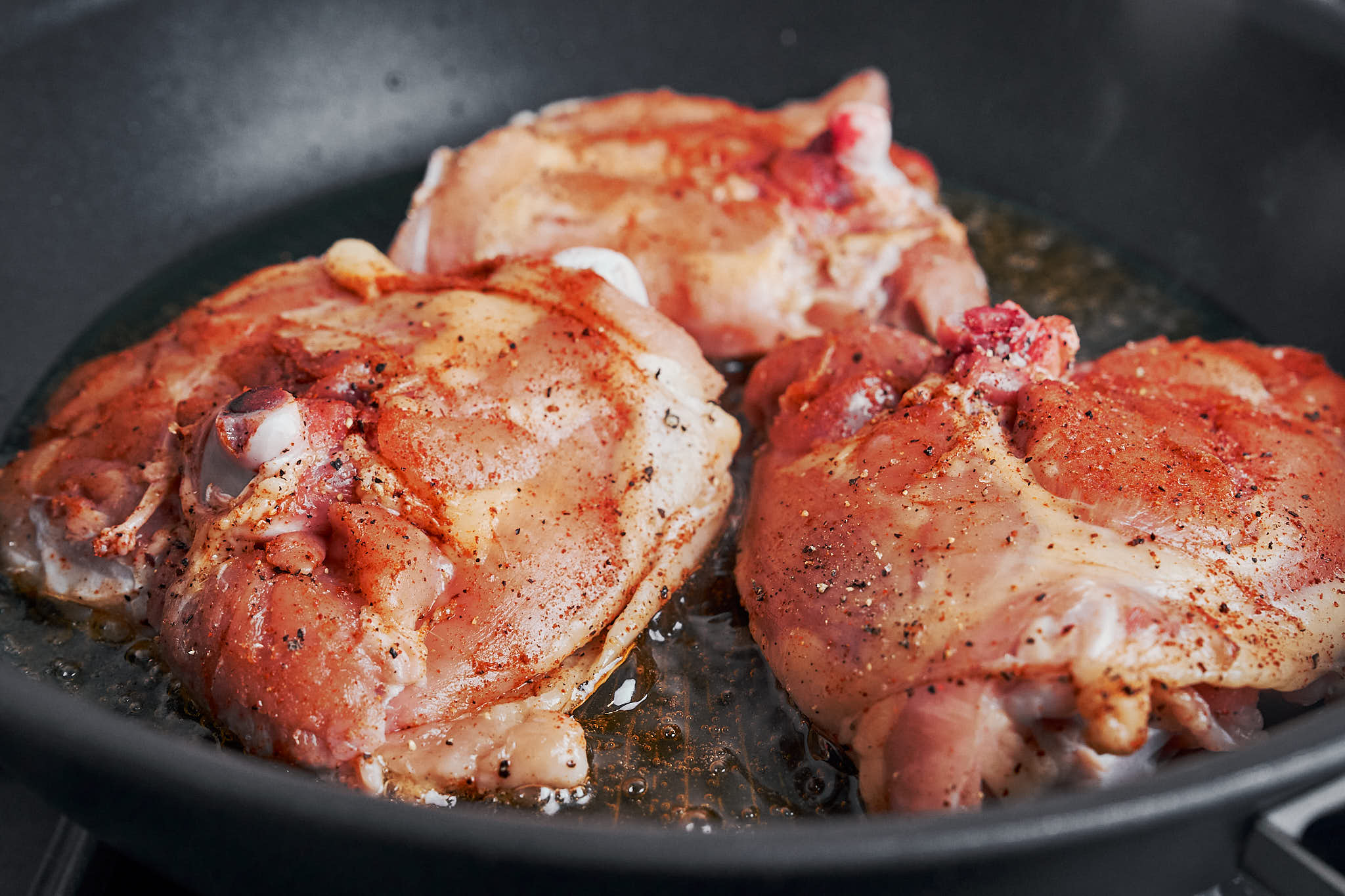 chicken thighs sizzling in the skillet