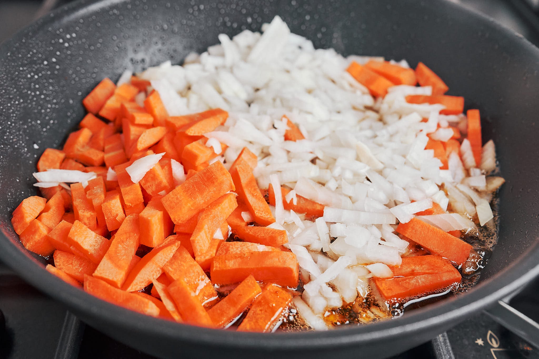 chopped onion and sliced carrot starting to cook in the skillet