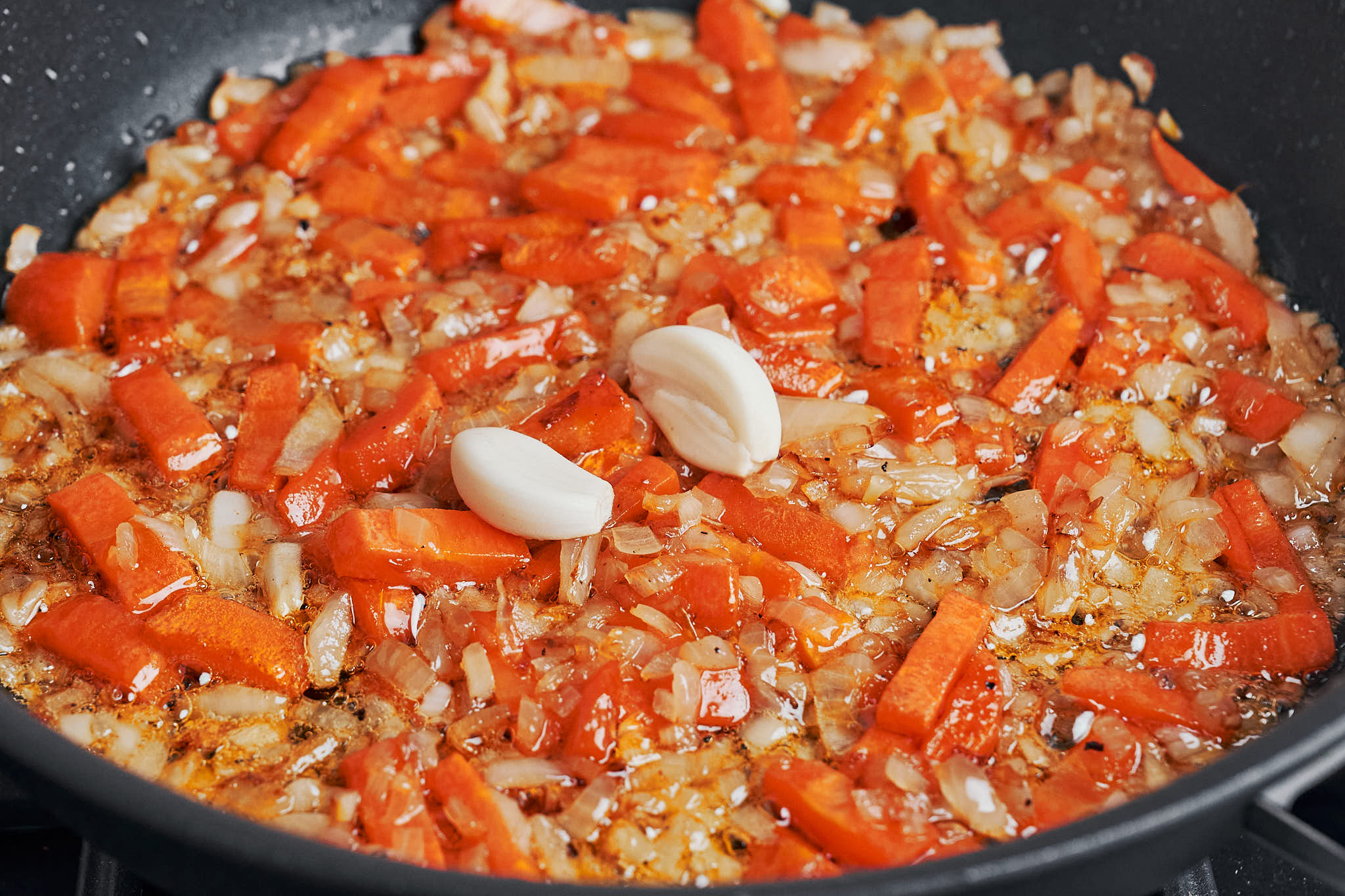 softened onion and carrot with whole garlic cloves in the skillet