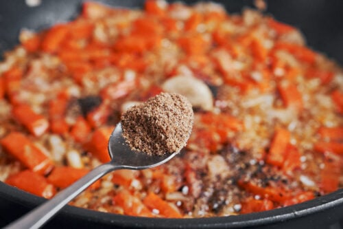 ground coriander being added to the skillet