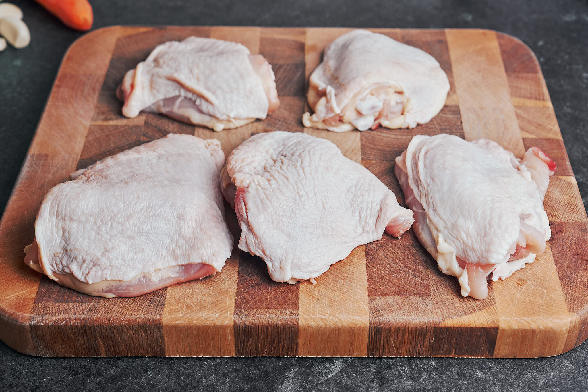 chicken thighs arranged on a cutting board before seasoning