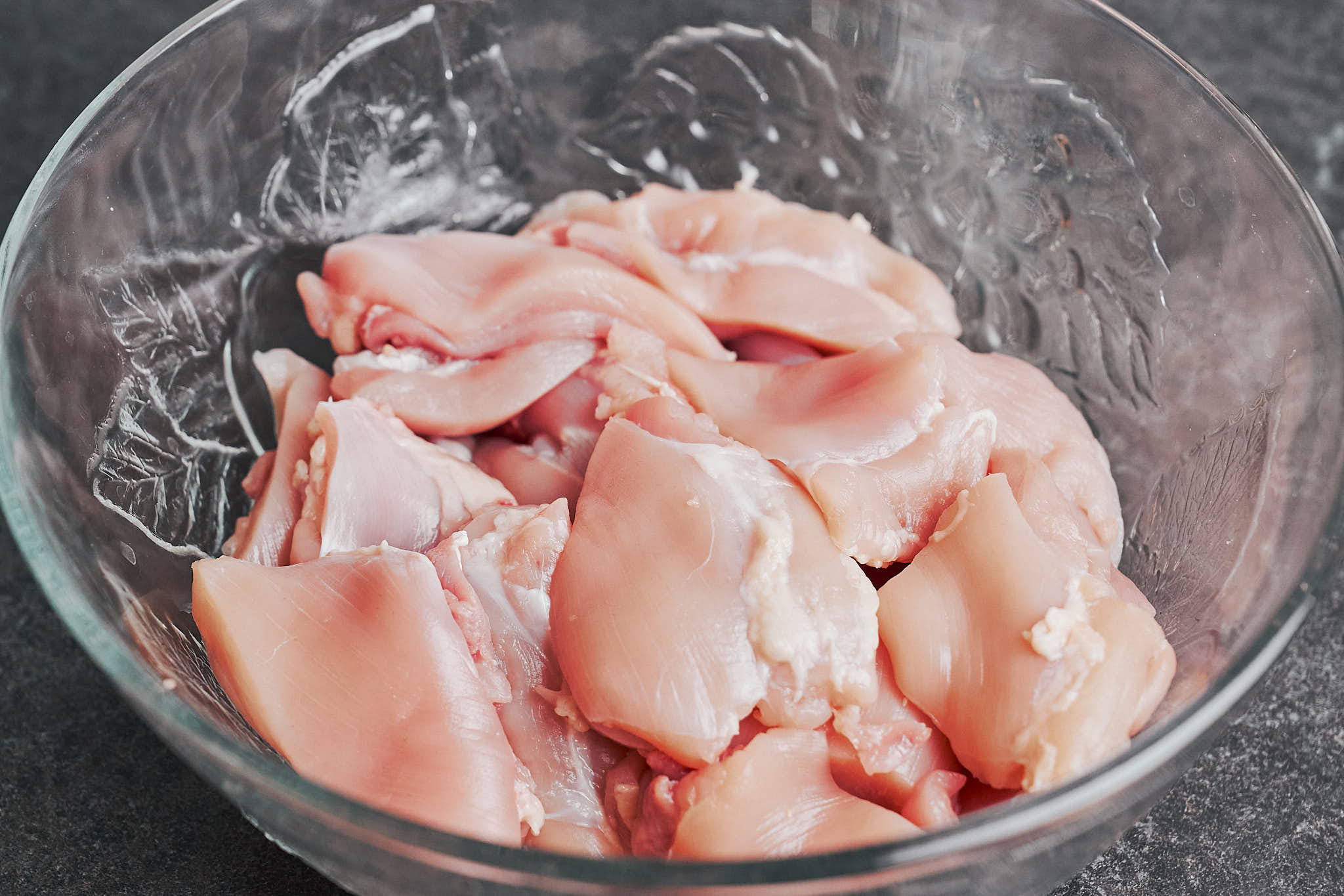 cut chicken thighs in a bowl ready for seasoning