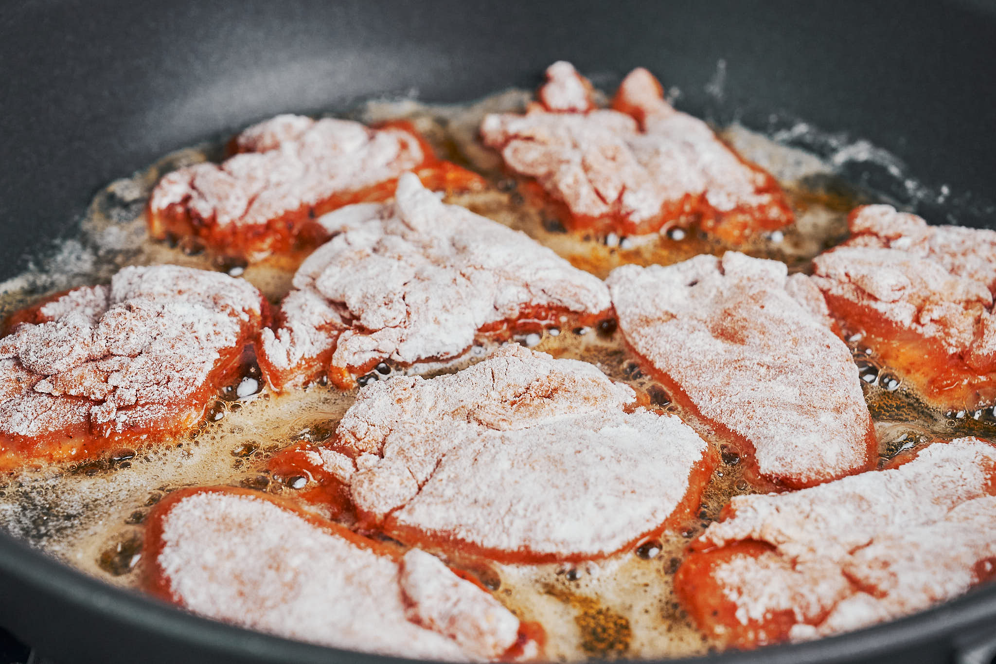 floured chicken pieces searing in a skillet until golden