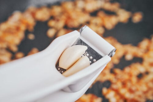 garlic being added to sautéed onions in skillet