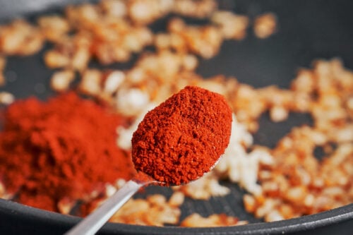 adding smoked paprika to onions in skillet