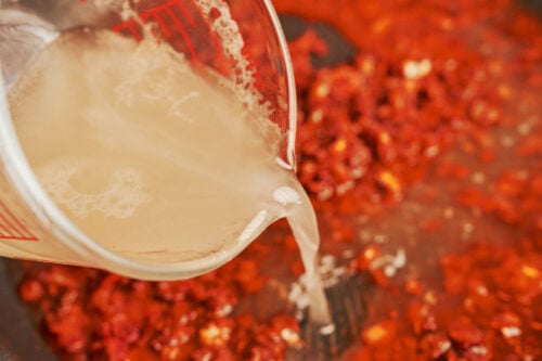 pouring chicken broth into skillet to build the sauce