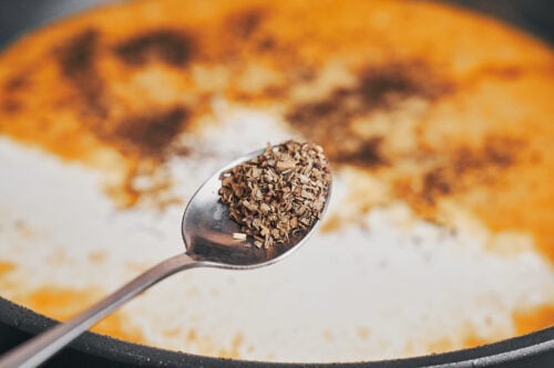 sprinkling oregano into the sauce as the creamy Dijon mixture comes together