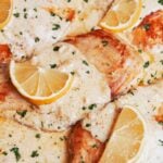 creamy lemon chicken in a skillet with a rich lemon cream sauce, lemon slices, and fresh parsley