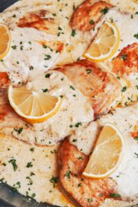 creamy lemon chicken in a skillet with a rich lemon cream sauce, lemon slices, and fresh parsley