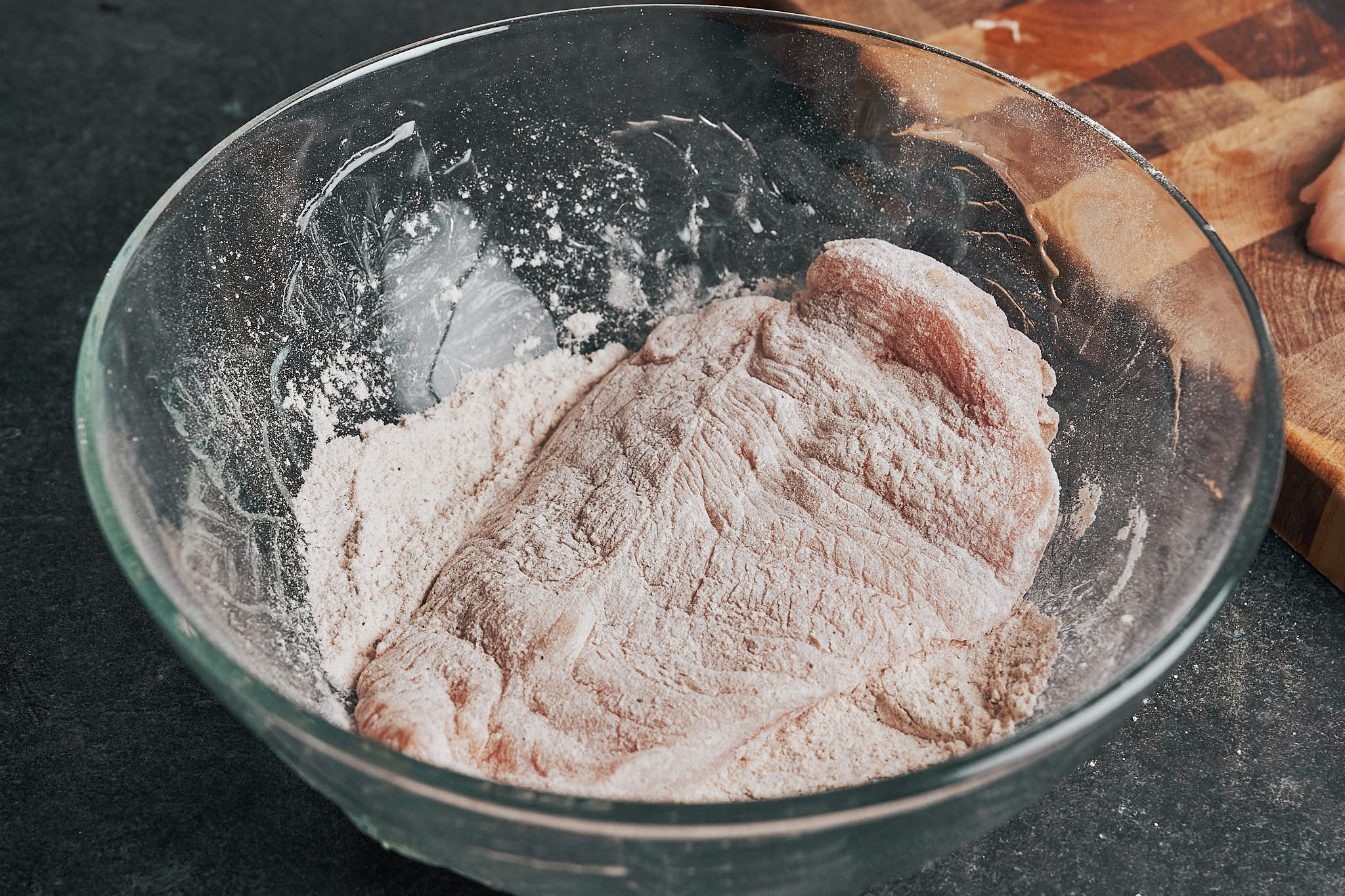 coating a chicken cutlet in the seasoned flour before pan searing