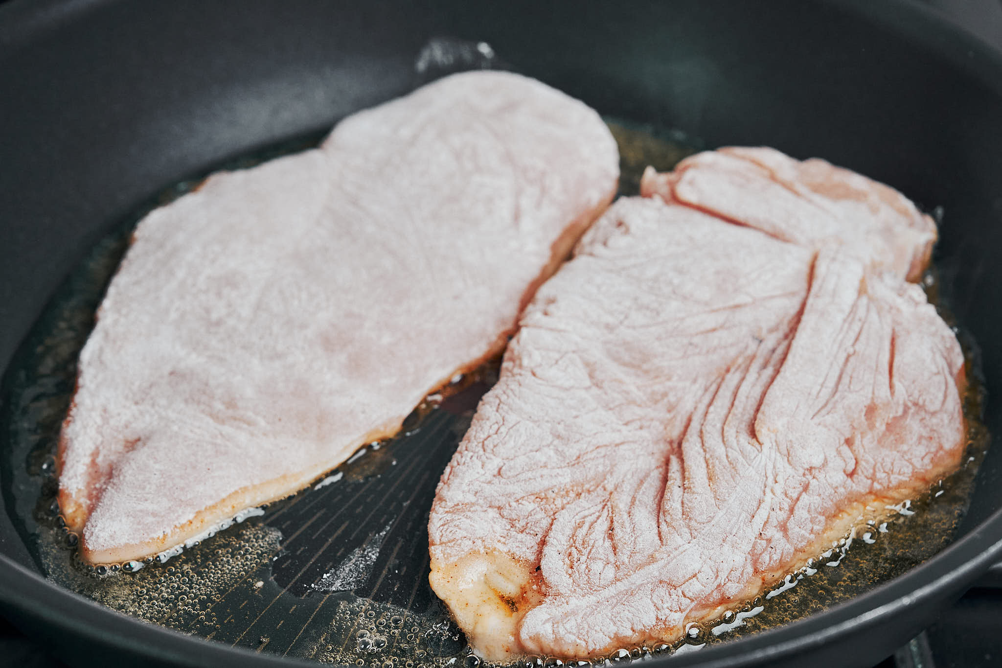 chicken cutlets searing in a hot skillet until lightly golden