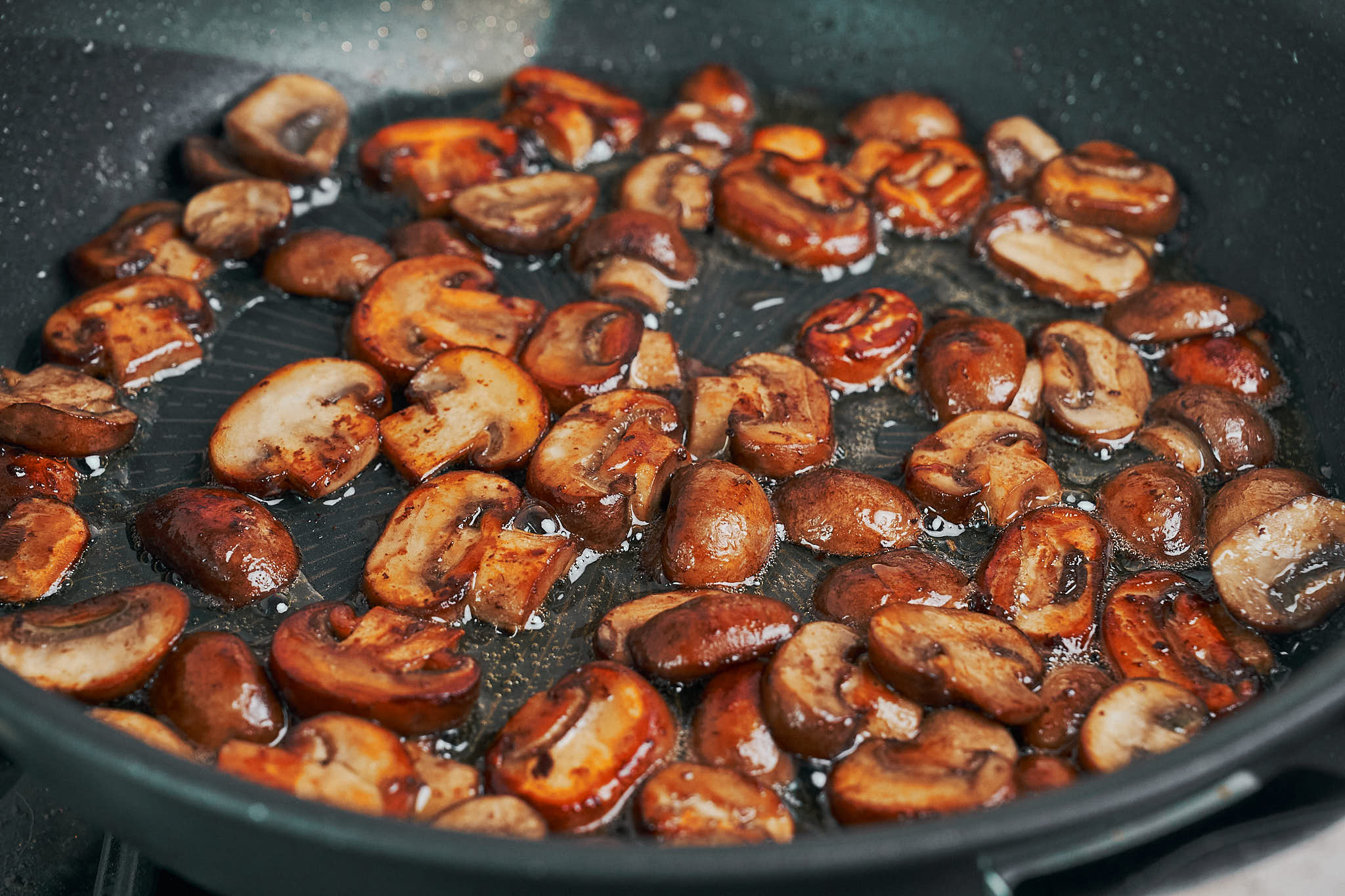 cremini mushrooms browned in butter in a pan