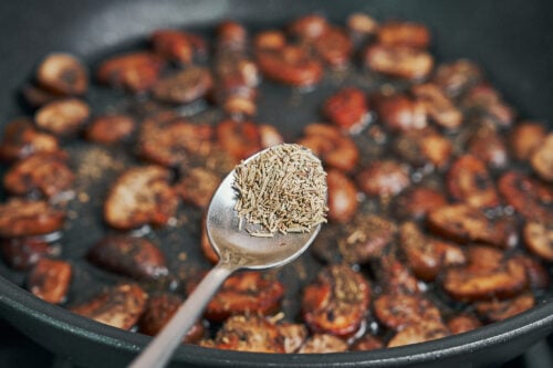 dried rosemary added to mushrooms in skillet