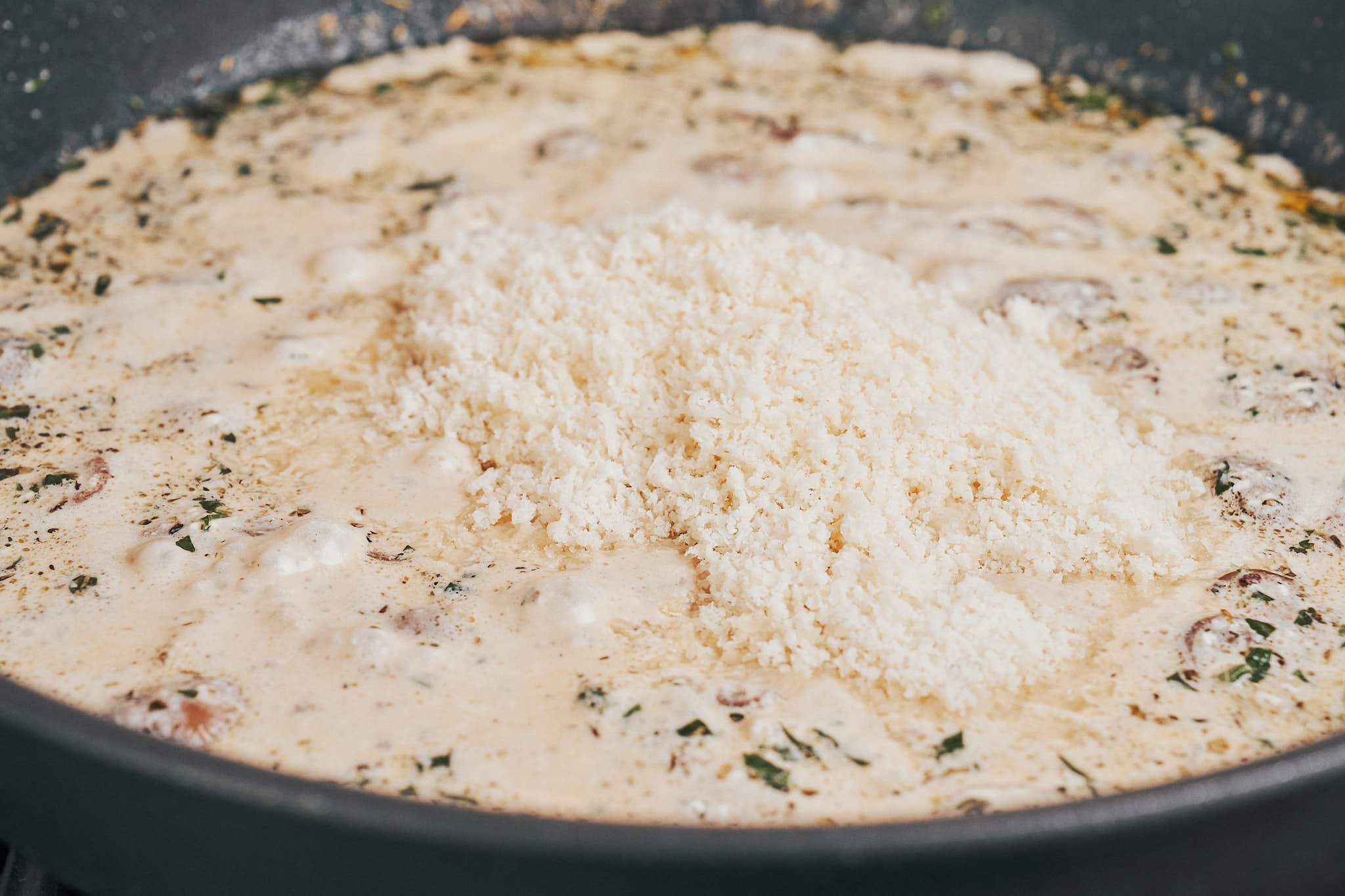freshly shredded Parmesan melting into cream sauce