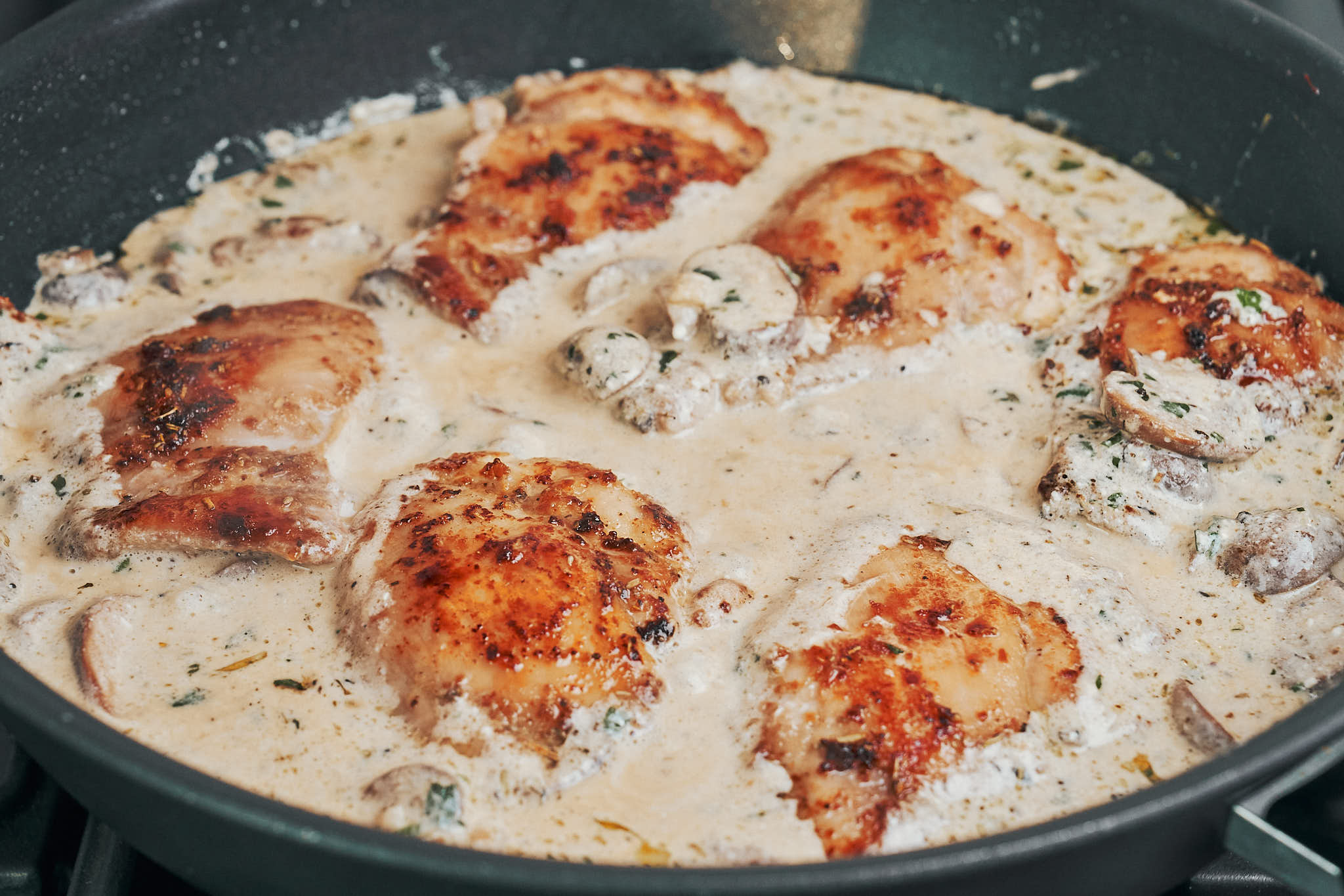 chicken thighs finished in a creamy garlic mushroom sauce in skillet