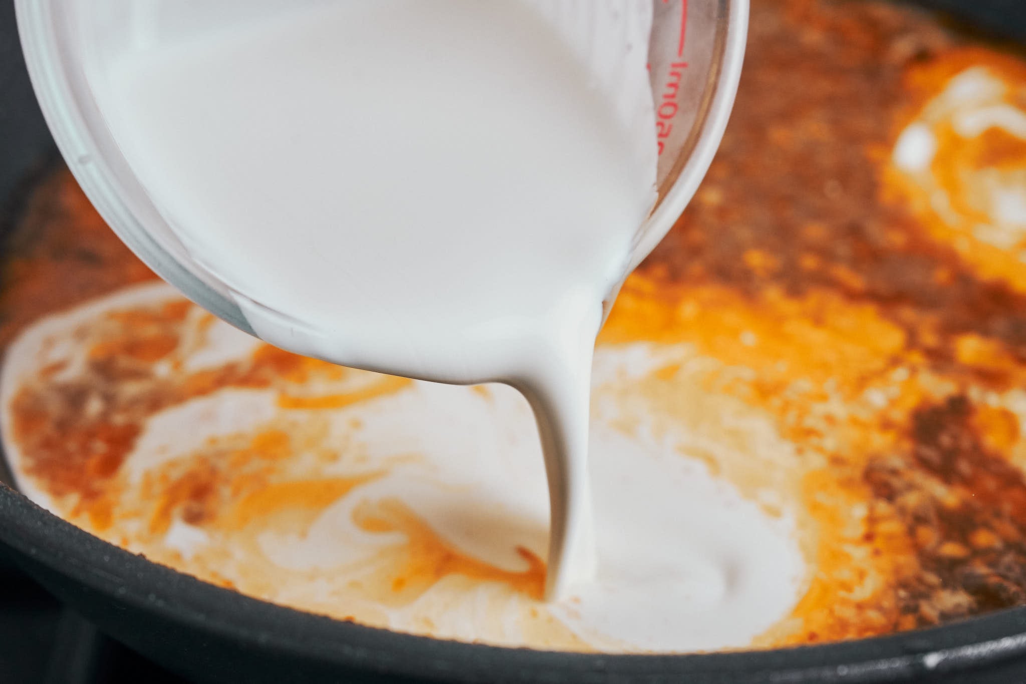 pouring heavy cream into the skillet to create a creamy sauce