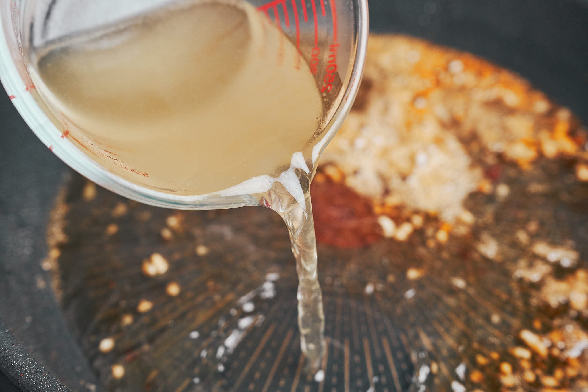 adding chicken broth to the skillet to start the creamy sauce