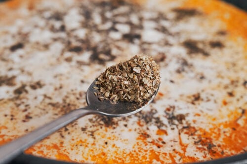 adding dried oregano to the creamy sauce for extra flavor