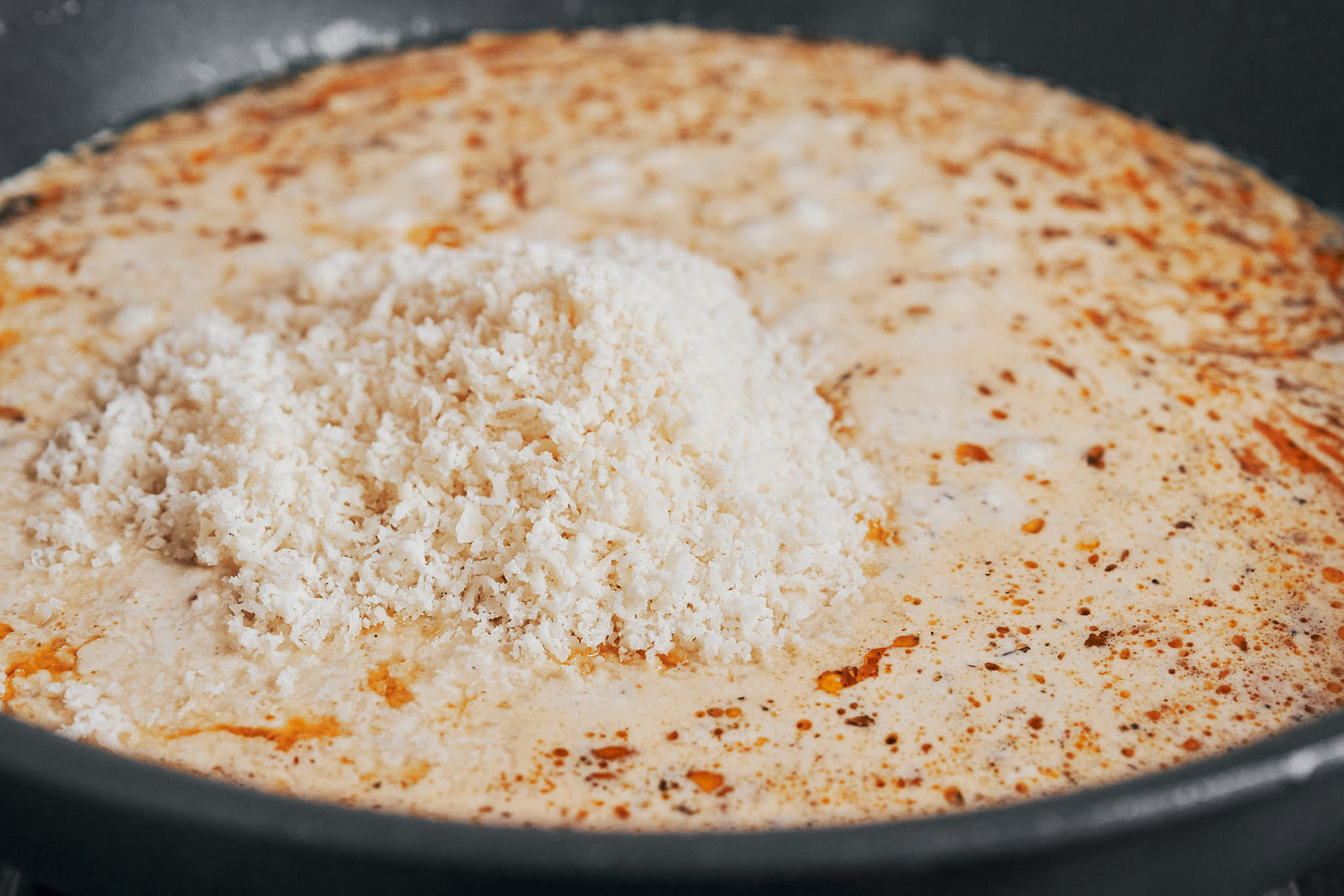 adding freshly grated Parmesan to the creamy sauce