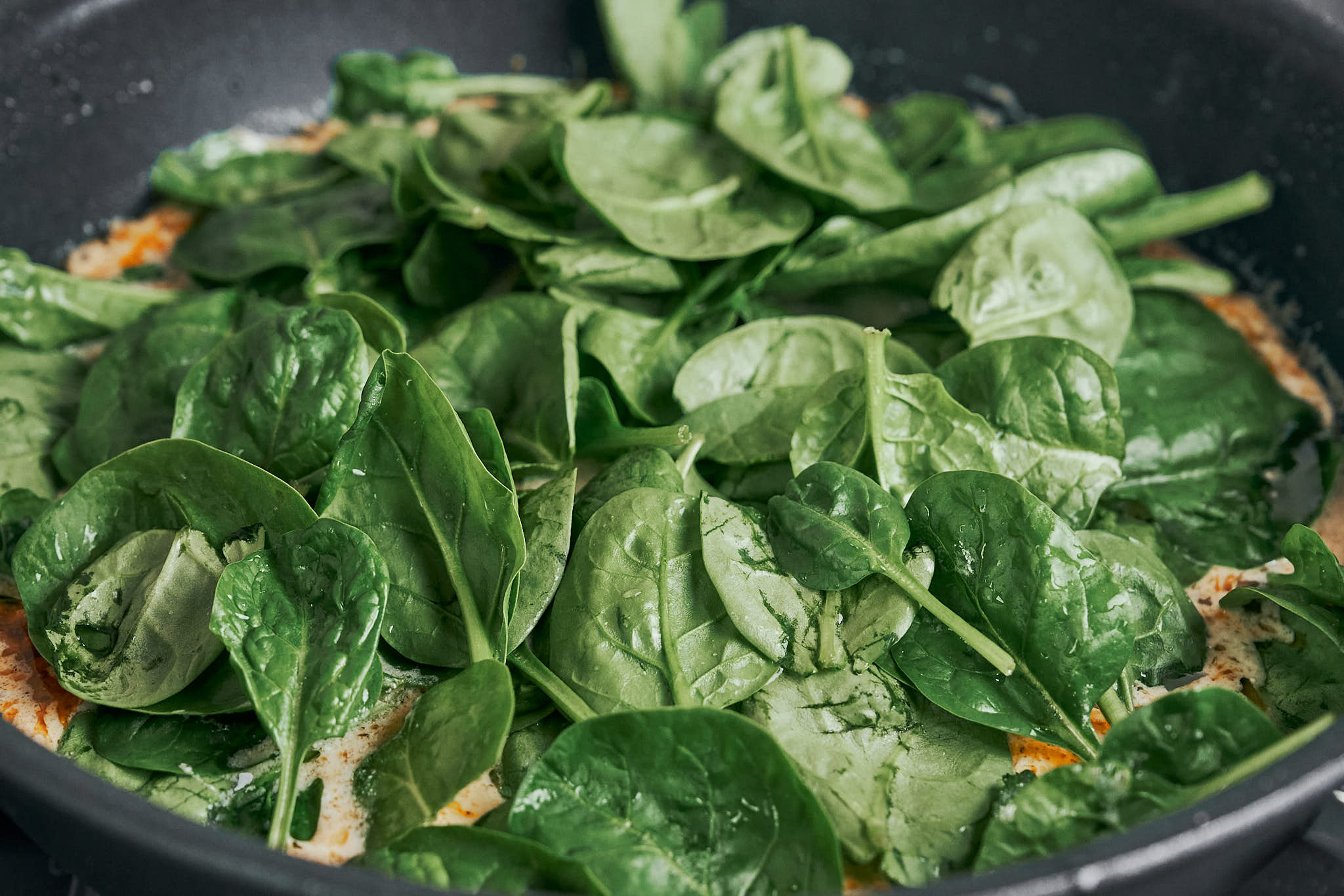 adding fresh spinach to the skillet before it wilts into the creamy sauce