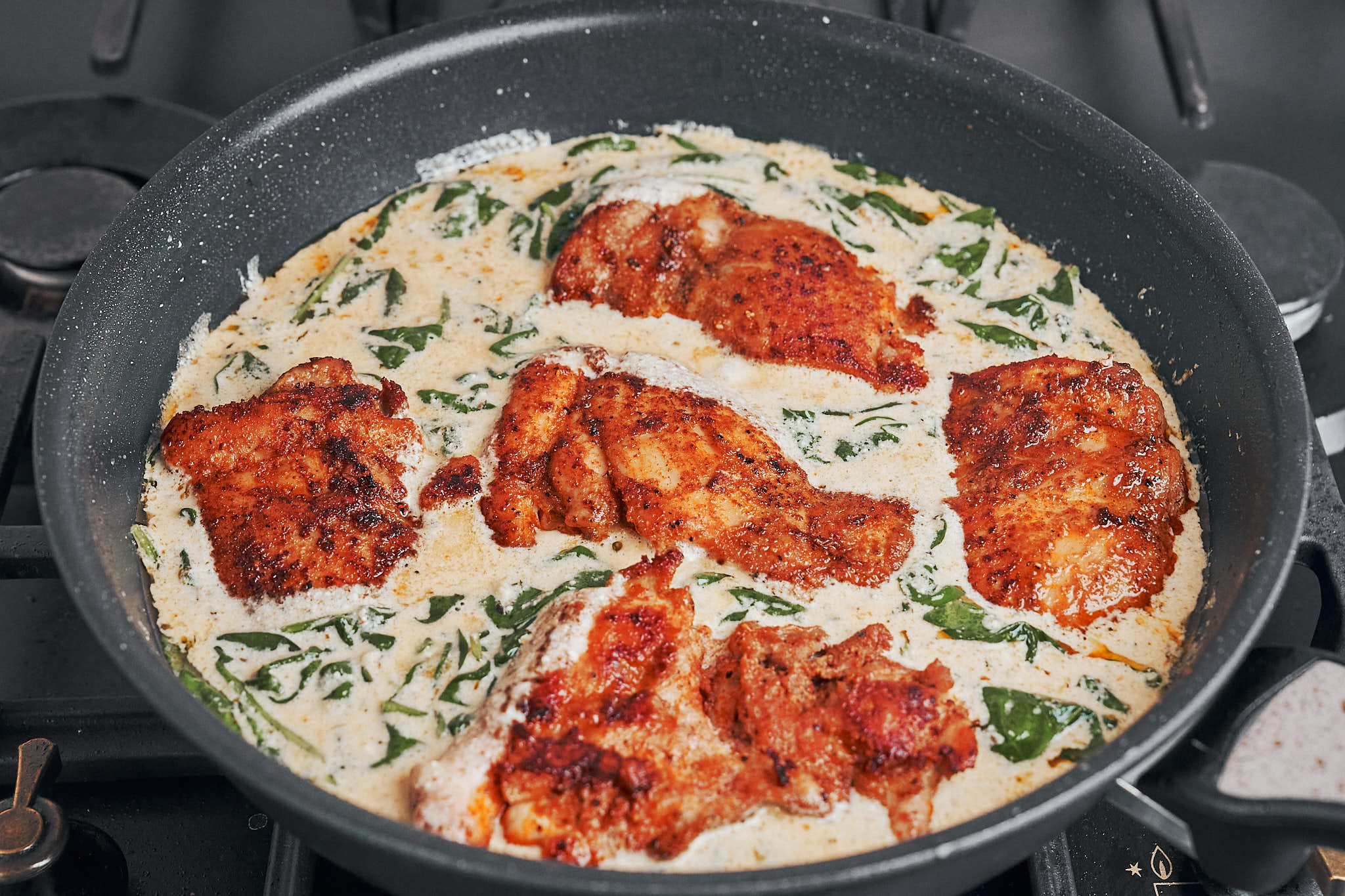 chicken simmering in a creamy spinach parmesan sauce