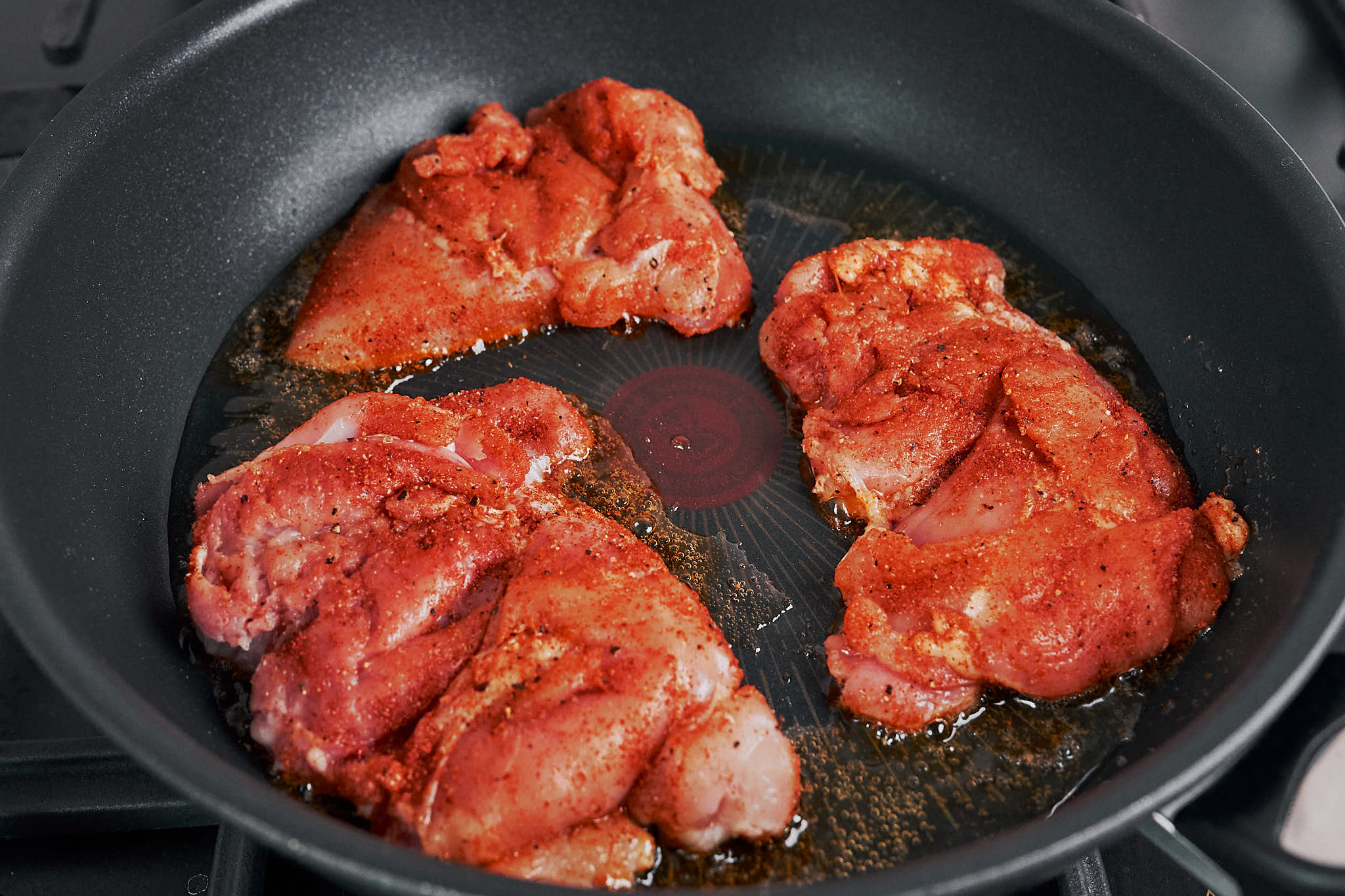 seasoned chicken thighs cooking in a skillet to build flavor for creamy spinach chicken