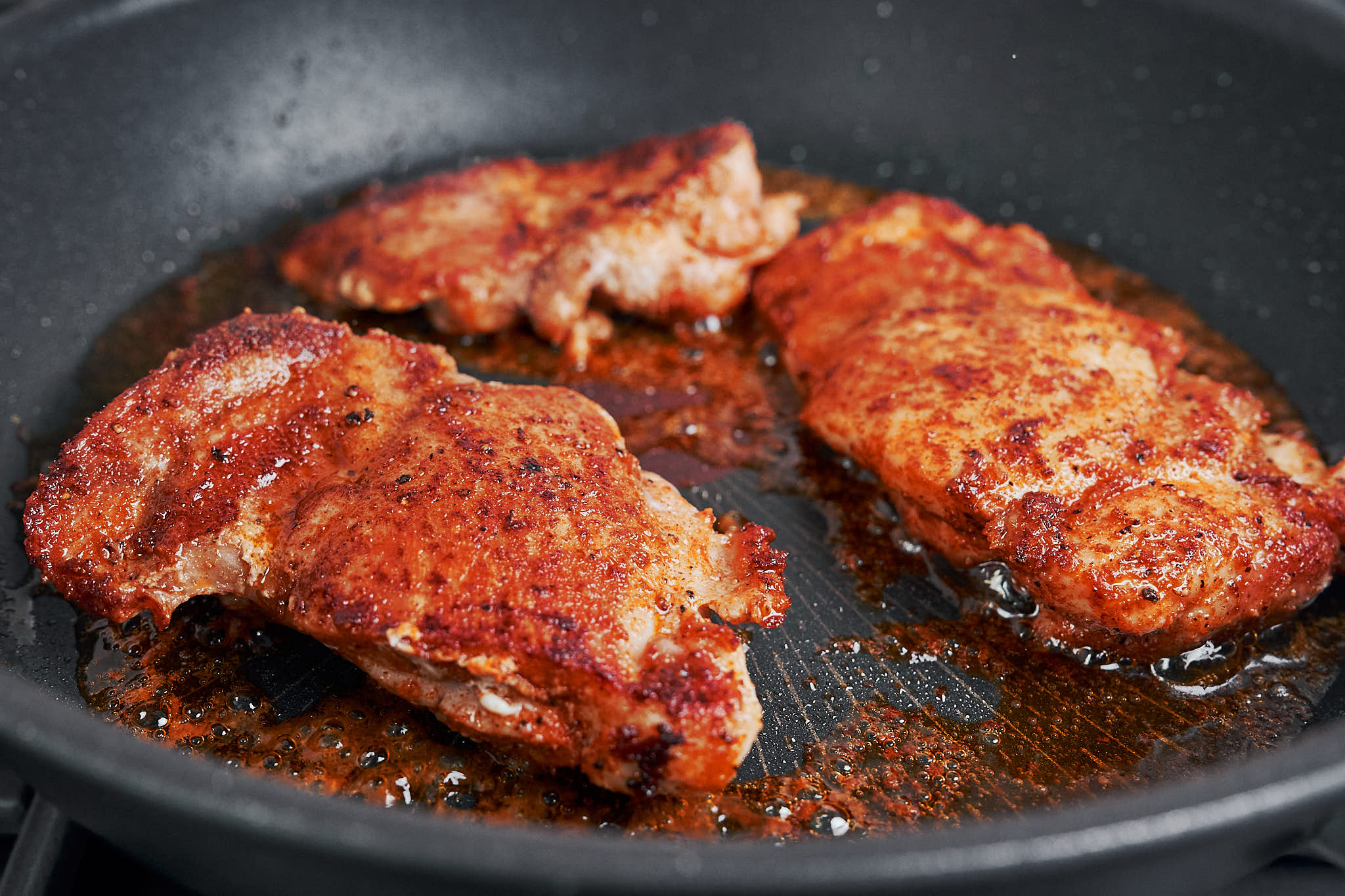 chicken thighs developing a golden crust while searing in the skillet