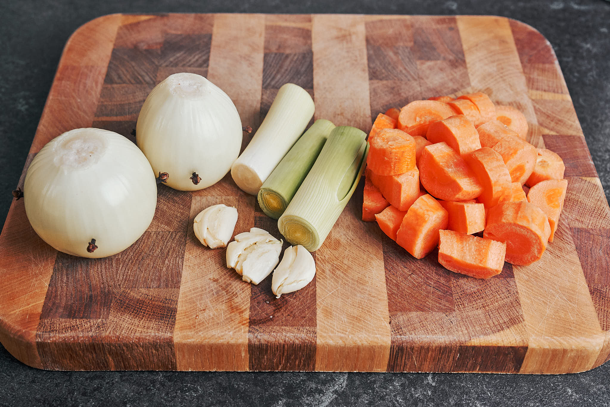 onions with cloves, sliced carrots and leek waiting on the board before cooking the beef stew