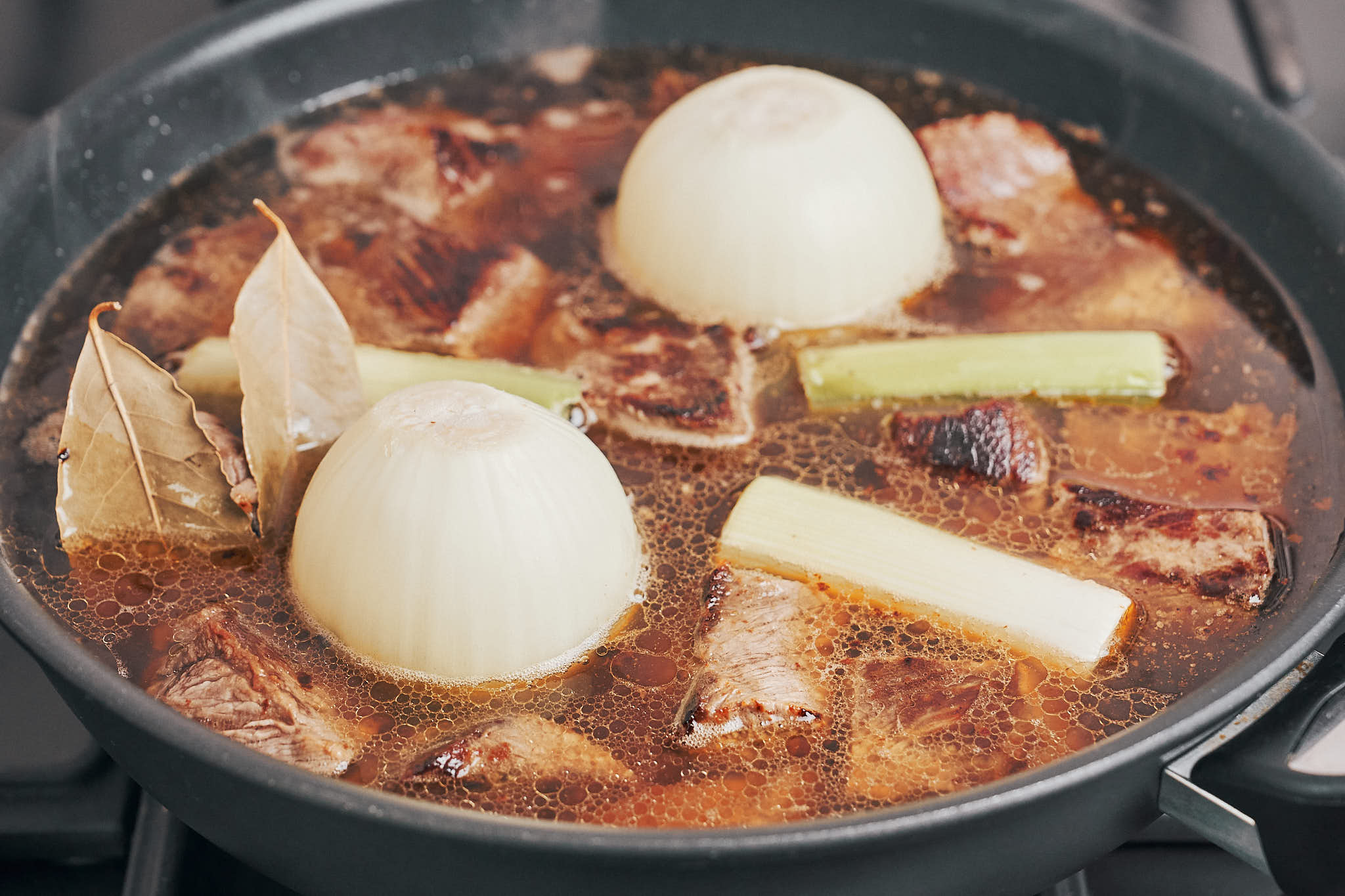 the stew starting to simmer with onions and aromatics