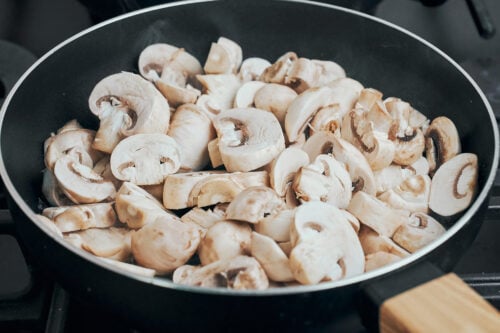 sliced mushrooms just added to the pan for sautéing