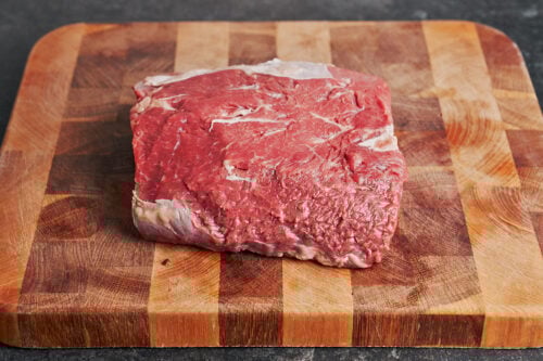 beef chuck on the cutting board before cutting it into stew pieces