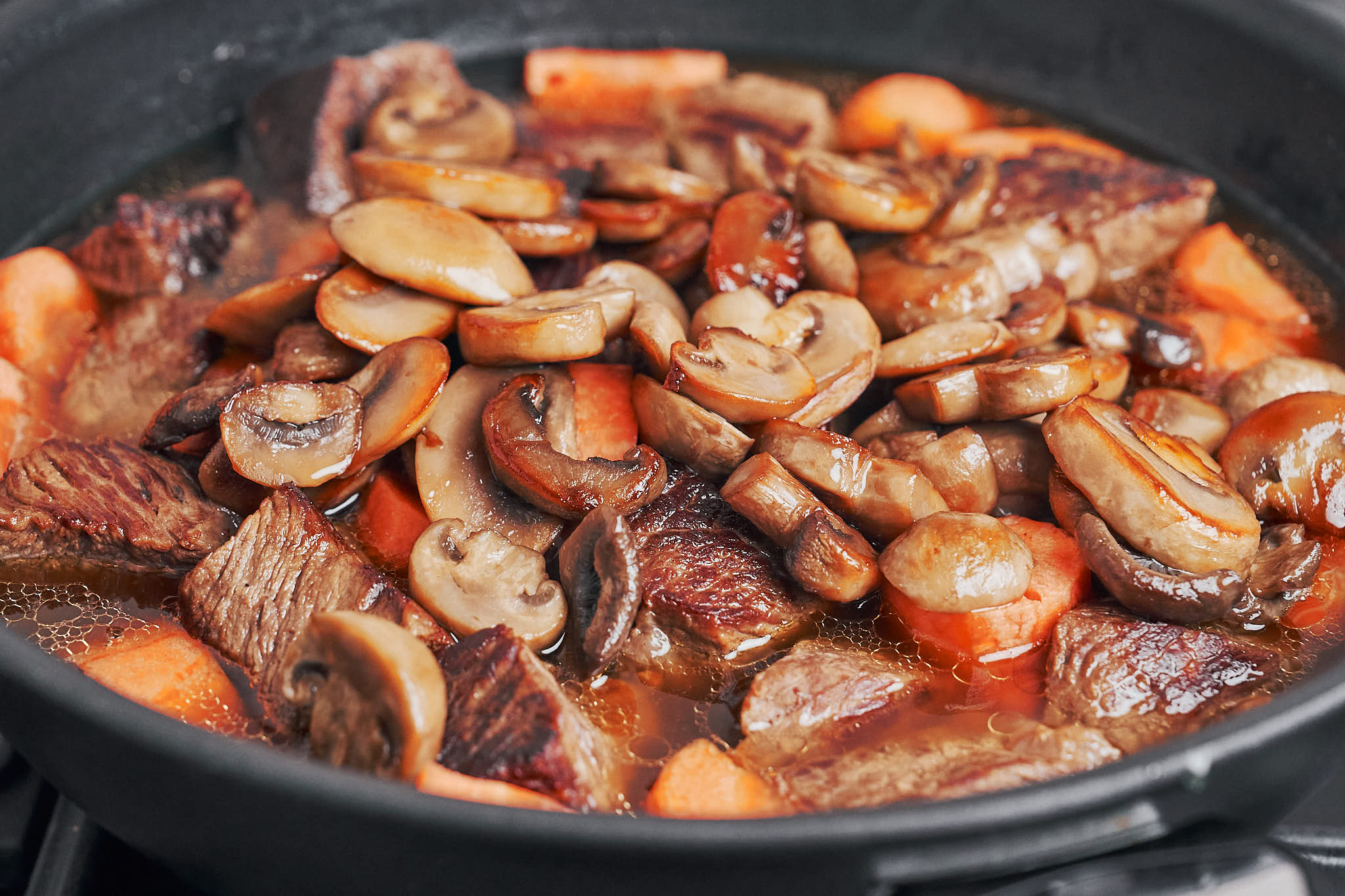 stew coming together with beef, mushrooms and carrots