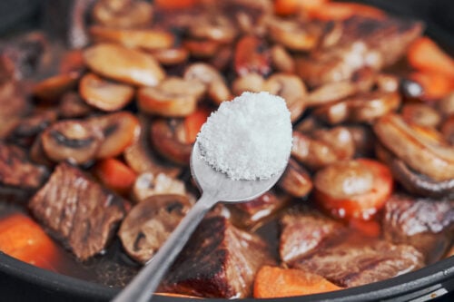 sprinkling salt over the stew to balance the flavor