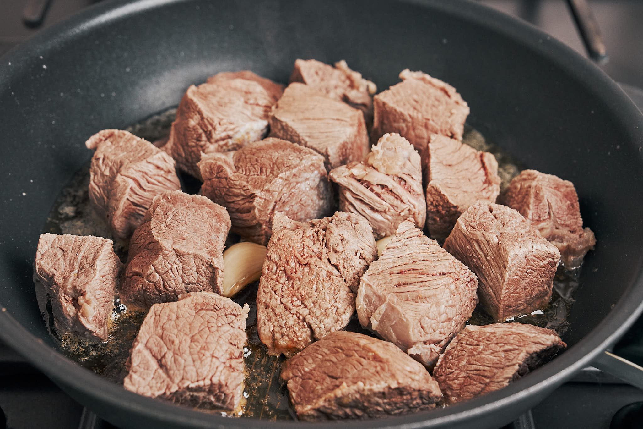 beef cooking in butter and garlic at the start of the browning step