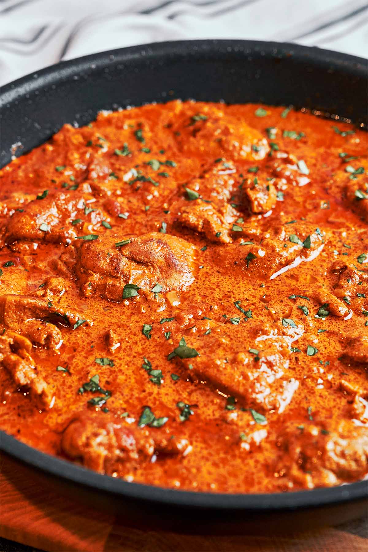 Creamy butter chicken finished in a skillet with tender chicken pieces, rich tomato cream sauce, and fresh parsley