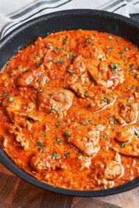 Creamy butter chicken in a skillet with tender chicken pieces, fresh parsley, and a rich tomato cream sauce