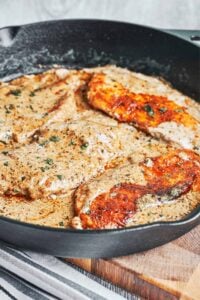 Creamy herb chicken in a skillet with golden seared chicken breasts coated in a rich garlic herb cream sauce and finished with fresh parsley