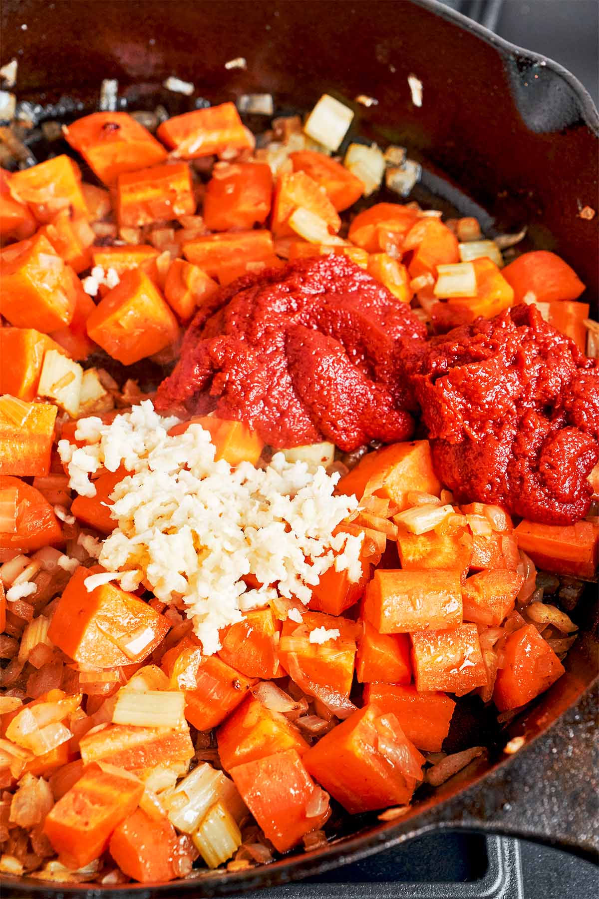 Tomato paste and minced garlic added to the vegetables before simmering the beef stew.